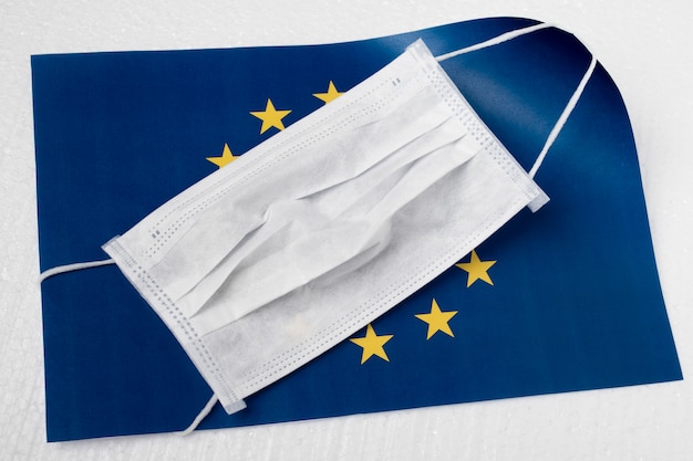 Coronavírus na Europa. Máscara antibacteriana médica no fundo da bandeira da União Europeia