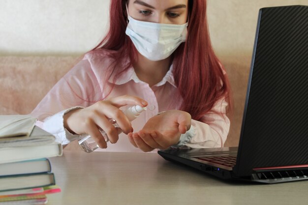 Foto coronavirus. quarantäne. online-ausbildung und freiberufliche tätigkeit. laptop und mädchen reinigen ihrer hände mit desinfektionsgel. coronavirus-pandemie in der welt.