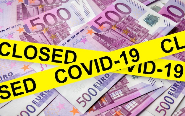Coronavirus- und Geschäftskonzept-Warnband auf Euro-Geldstapel-Weltwirtschaft, die durch den Ausbruch des Corona-Virus getroffen wird