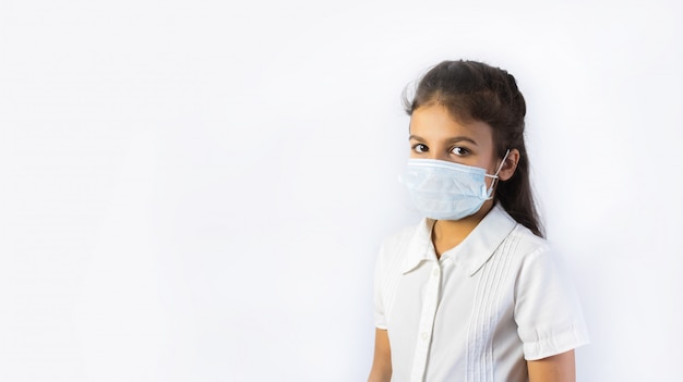 Coronavirus- und Luftverschmutzungskonzept. Kleines indisches oder pakistanisches Mädchen, das Maske zum Schutz pm2.5 trägt. Isoliert
