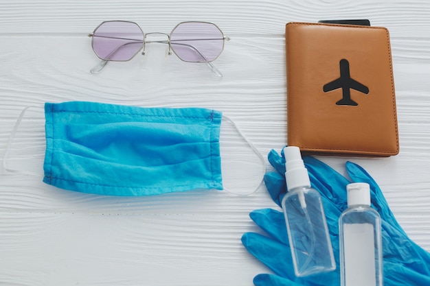 Foto coronavirus verano 2020 mascarilla azul guantes antisépticos y desinfectantes pasaporte gafas de sol sobre fondo blanco viaje seguro en 2020 nueva normalidad