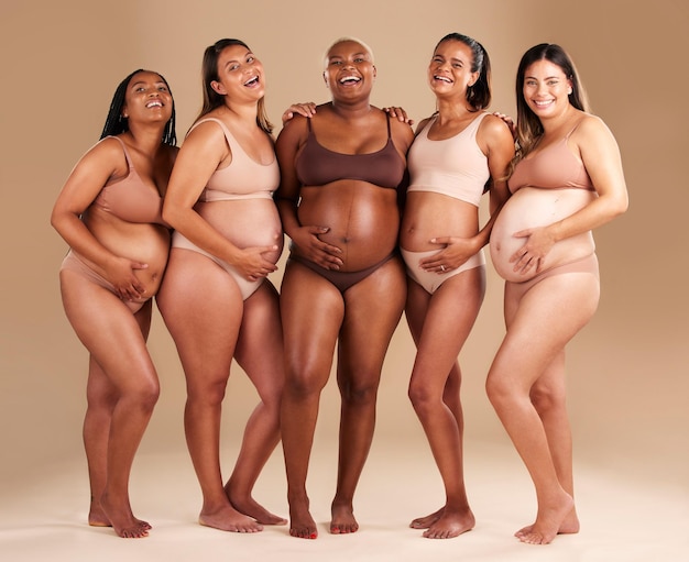 Corpo de gravidez e retrato de amigos felizes em um estúdio para maternidade de diversidade e bem-estar pré-natal beleza de maternidade e mulheres grávidas mostrando barriga de bebê juntos por fundo bege