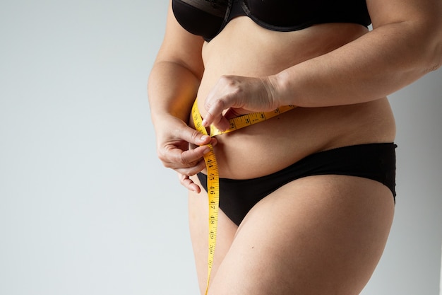 corpo de mulher curvilínea de meia-idade medindo a barriga