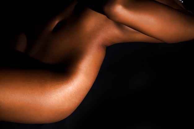 Foto corpo de mulher jovem nu bonito deitado na frente do fundo preto
