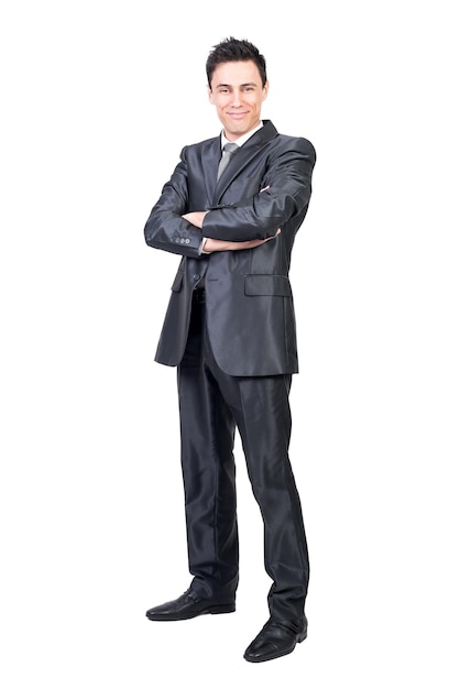 Corpo inteiro de homem otimista em terno formal olhando para a câmera com sorriso em pé com os braços cruzados isolados no fundo branco