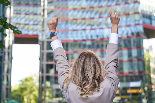 Corporate People Rückansicht der Geschäftsfrau, die die Hände hochhebt, um das Ziel zu feiern