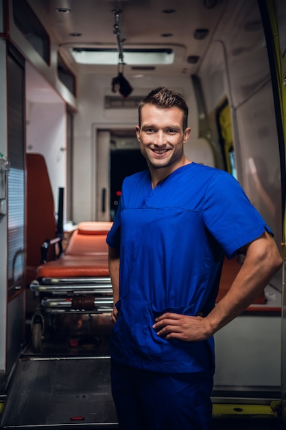 Corpsman em um uniforme azul, sentado em um carro de ambulância sorrindo