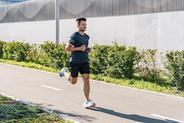 Corre solo en una cinta de correr en la ciudad Motivación y estilo de vida activo Un joven trotando en camiseta
