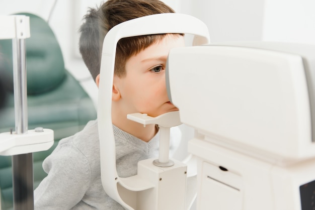 Corrección de la visión en un niño. Cara de primer plano del niño paciente. Equipo súper moderno en una clínica moderna para examen ocular