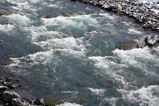 Corredeiras de rios de montanha com água rápida e grandes pedregulhos rochosos fluxo rápido de um rio de montanha na primavera