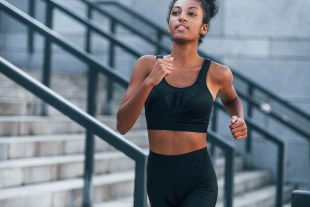 Corredor activo Joven mujer afroamericana en ropa deportiva tiene entrenamiento al aire libre durante el día