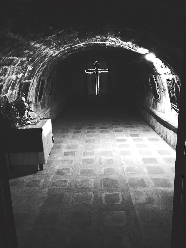 Foto corredor arqueado com cruz à distância