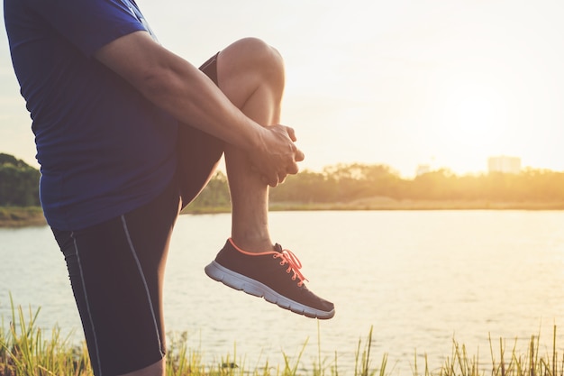 Corredor asiático calienta su cuerpo antes de comenzar a correr en la carretera