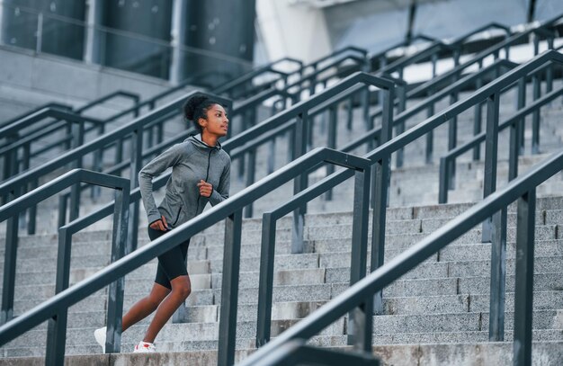 Corredor ativo Jovem afro-americana em roupas esportivas tem treino ao ar livre durante o dia