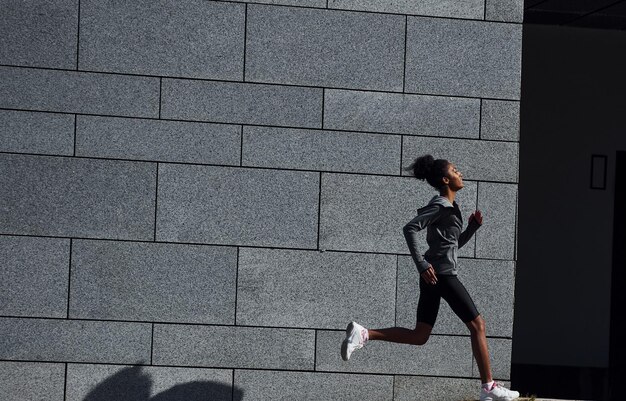 Corredor ativo Jovem afro-americana em roupas esportivas tem treino ao ar livre durante o dia