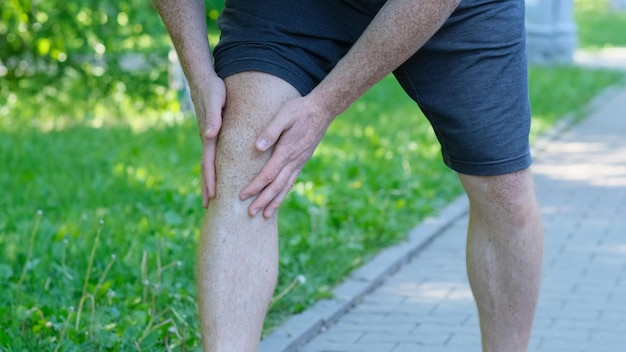 Corredor atlético masculino tocando o pé com dor devido a um tornozelo torcido