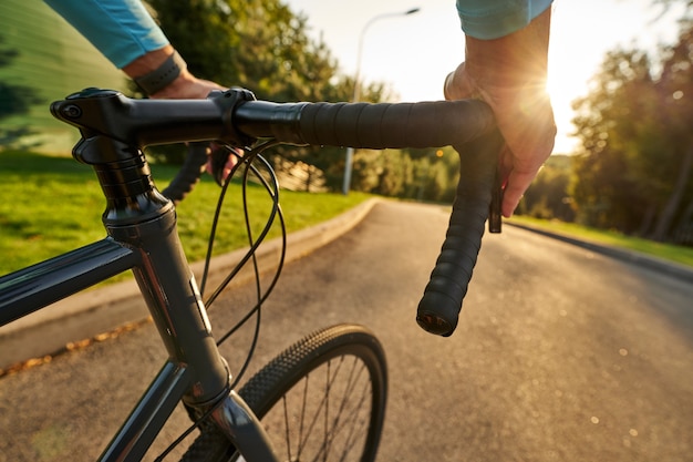 Foto corredor de bicicleta masculino profesional montando su bicicleta de carretera en el parque al atardecer. deporte, ciclismo.