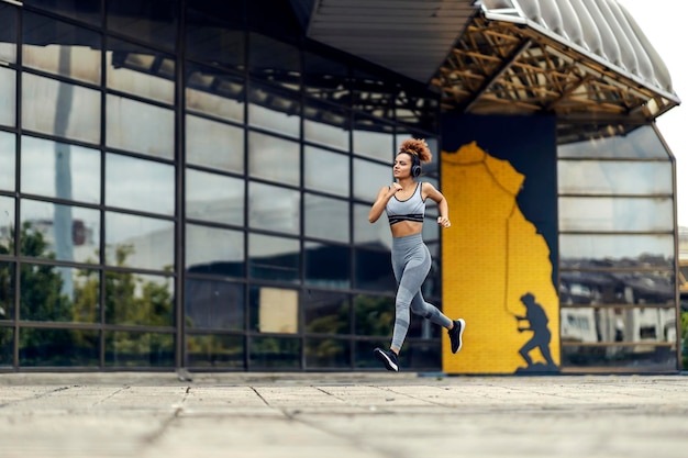 Un corredor corriendo en la ciudad y preparándose para un maratón mientras escucha música con auriculares