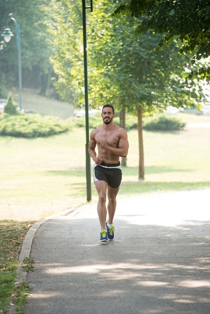 Corredor culturista trotar durante el entrenamiento al aire libre en el parque