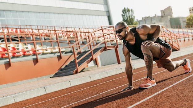 Corredor de atleta fazendo exercícios de alongamento na pista de corrida