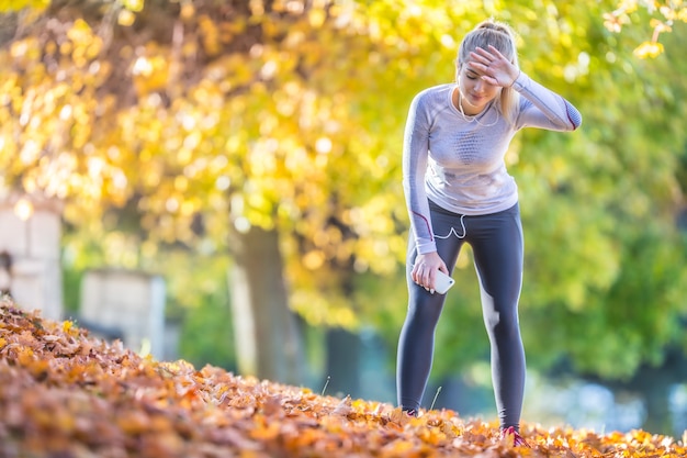 Corredor de atleta jovem cansado de respirar depois de correr em um belo parque colorido de outono.