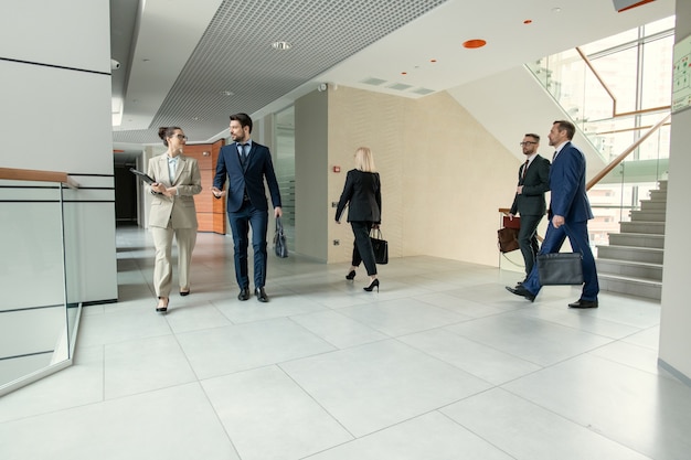 Foto corredor de escritório contemporâneo cheio de executivos correndo para o trabalho: colegas andando pelo corredor e discutindo projetos