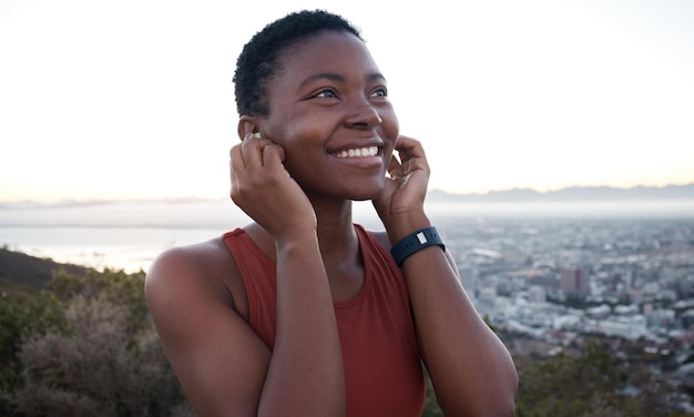 Corredor de fones de ouvido ou mulher negra na natureza para treinamento físico em execução ou exercício cardiovascular no podcast Cape Town Music ou atleta esportivo feliz pensando em metas ou rádio de streaming de destino