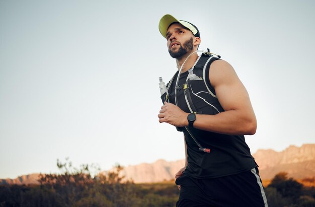 Corredor de homem de saúde e na natureza para treinamento de bem-estar e fitness com roupas esportivas sendo foco Exercício jovem atleta do sexo masculino e corrida ao ar livre para cardio saudável e aquecimento de treino e ar fresco