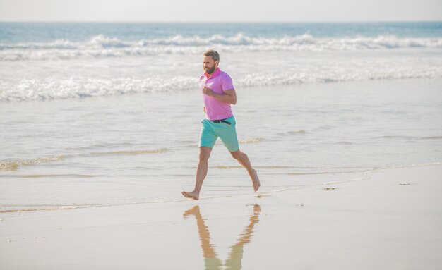 Corredor de homem desportivo adulto correndo na praia conquista ao ar livre