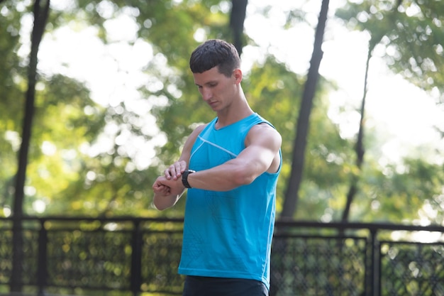 Corredor de homem em roupas esportivas, verificando o tempo no smartwatch