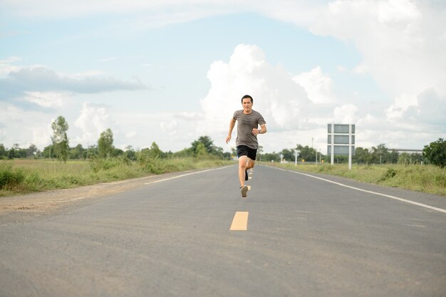 Corredor de homem na estrada para jovens saudáveis, executando o exercício na rua.