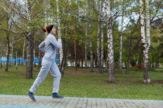 Corredor de mulher correndo no parque. Belo modelo de fitness desportivo durante o treino ao ar livre.