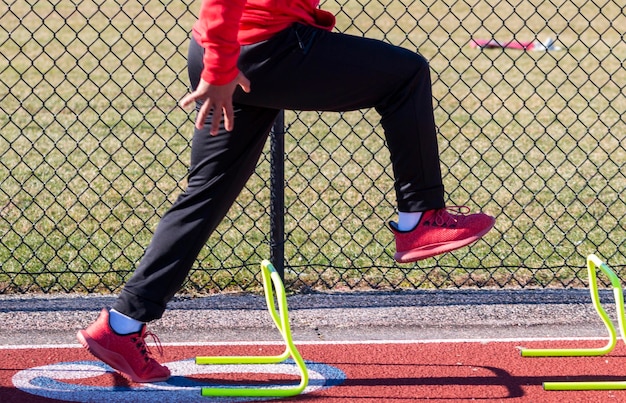 Corredor de pista de pé sobre mini obstáculos amarelos na posição a pré-formação de exercícios de treinamento de velocidade