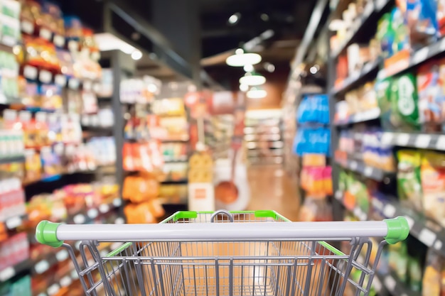 Corredor de supermercado e fundo de prateleiras de produtos com carrinho de compras vazio