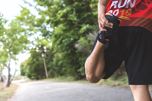 El corredor del deportista calienta su cuerpo antes de comenzar a correr en el roadpark con enfoque suave