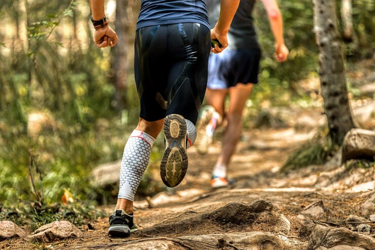 Foto corredor de espaldas en calcetines de compresión corriendo por el sendero de piedras