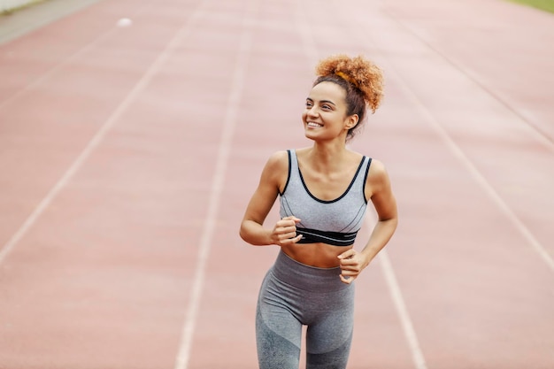 Un corredor feliz corre en la pista del estadio en el maratón