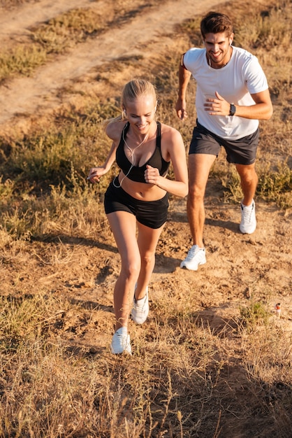 Corredor femenino atlético y modelo de fitness masculino corriendo juntos al aire libre