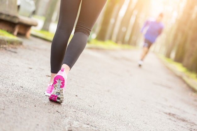 El corredor femenino calza el primer antes de correr en el parque.