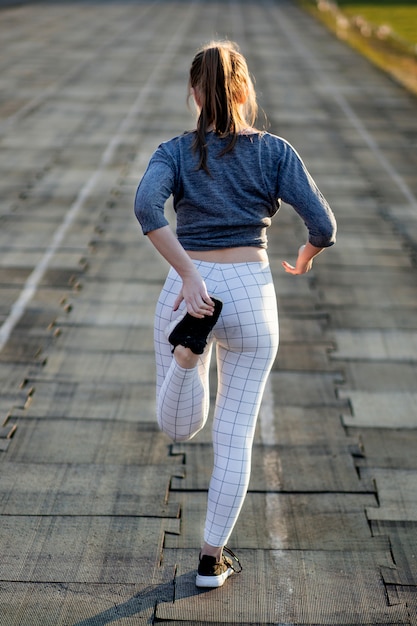 Corredor femenino estirando las piernas en la pista de atletismo