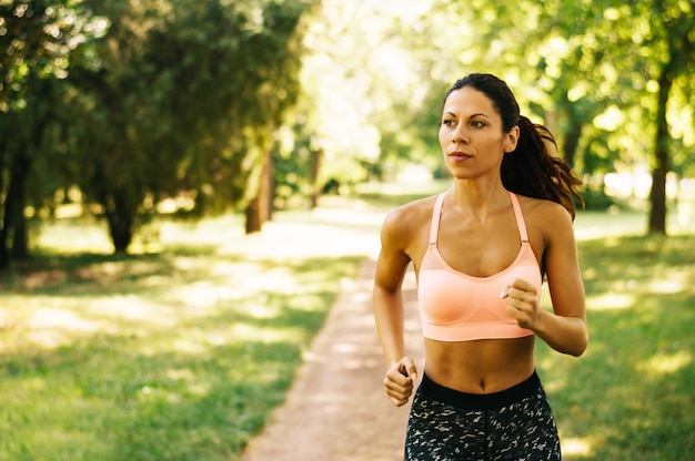 Corredor femenino que activa durante entrenamiento al aire libre en un parque