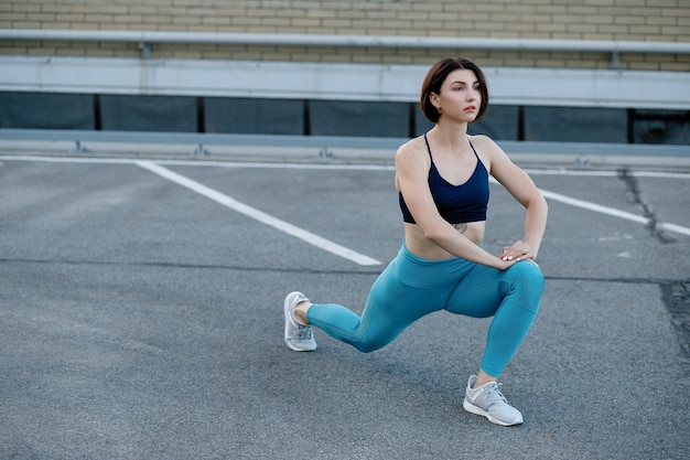 Corredor feminino alongamento após uma sessão de corrida na cidade. mulher jovem esportes fazendo uma pausa depois de uma corrida.