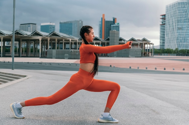 Corredor feminino fazendo alongamento em alta estocada antes do treino Estilo de vida ativo Copiar espaço