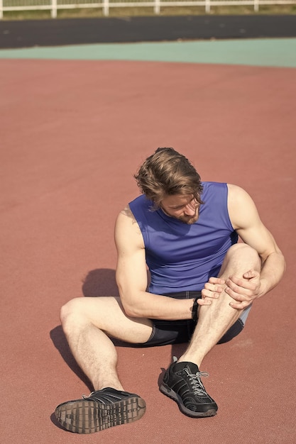 Foto corredor herido en la pista de atletismo sintiendo dolor de pierna rota