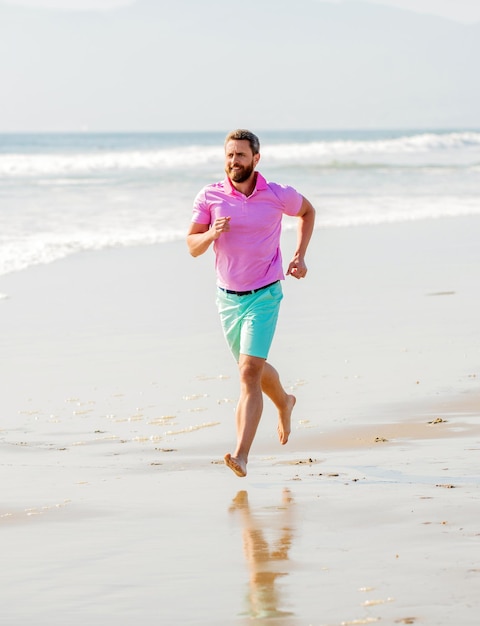 Corredor de hombre deportivo corriendo en la playa de verano al aire libre