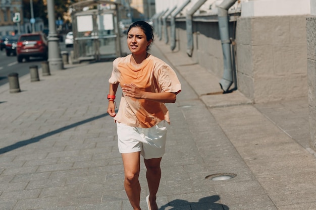 Corredor jovem indiana correndo com uma camiseta molhada e suada na rua da cidade