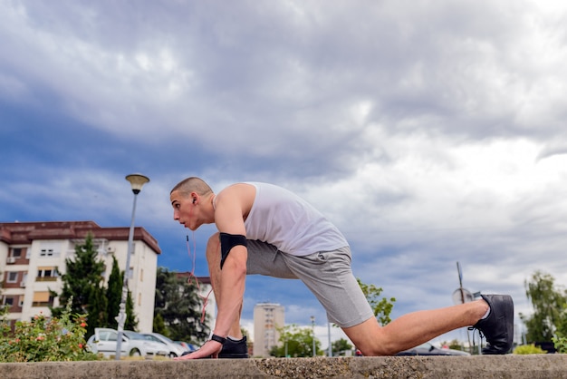 Corredor joven del hombre de la aptitud que estira las piernas antes de correr