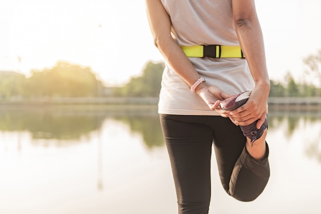 Foto corredor joven de la mujer de la aptitud que estira las piernas antes de correr en ciudad