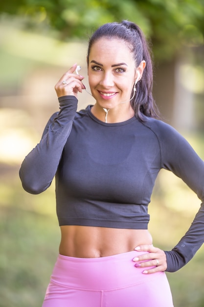 Corredor joven mujer deportiva con una bonita sonrisa antes de correr con auriculares escucha música motivacional.