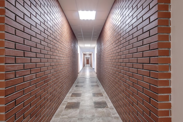 Corredor longo vazio branco com paredes de tijolo vermelho para sala de escritório no interior do escritório ou clínica de apartamentos modernos
